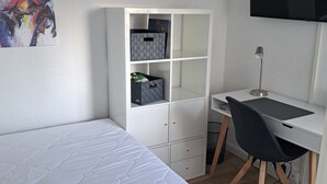Une chambre à coucher avec un lit, un bureau, une chaise, une télévision et une bibliothèque.