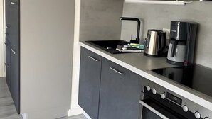 Une cuisine moderne avec des meubles gris, un four noir et une machine à café en acier inoxydable.
