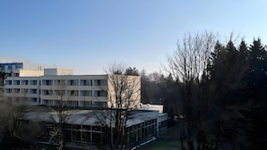 Un bâtiment moderne doté d’un toit plat, entouré d’arbres et d’une zone herbeuse.
