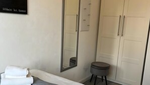 Une chambre d’hôtel avec deux lits, un grand miroir, une armoire et un petit tabouret.