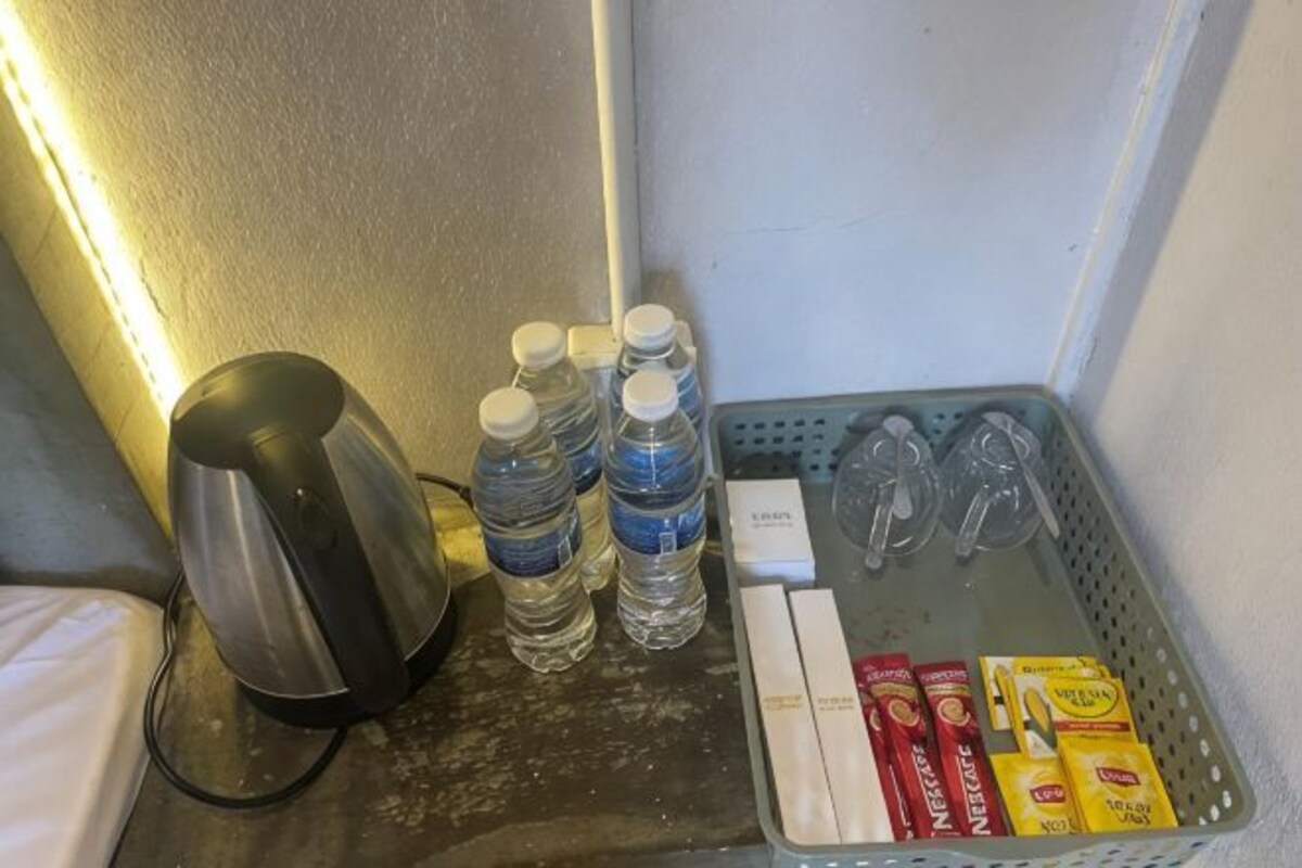 A minibar with a kettle, bottled water, and condiments.