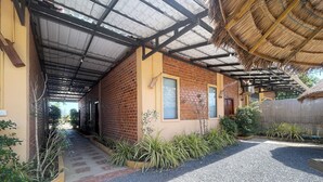 A covered outdoor area with a brick building, gravel path, and potted plants.