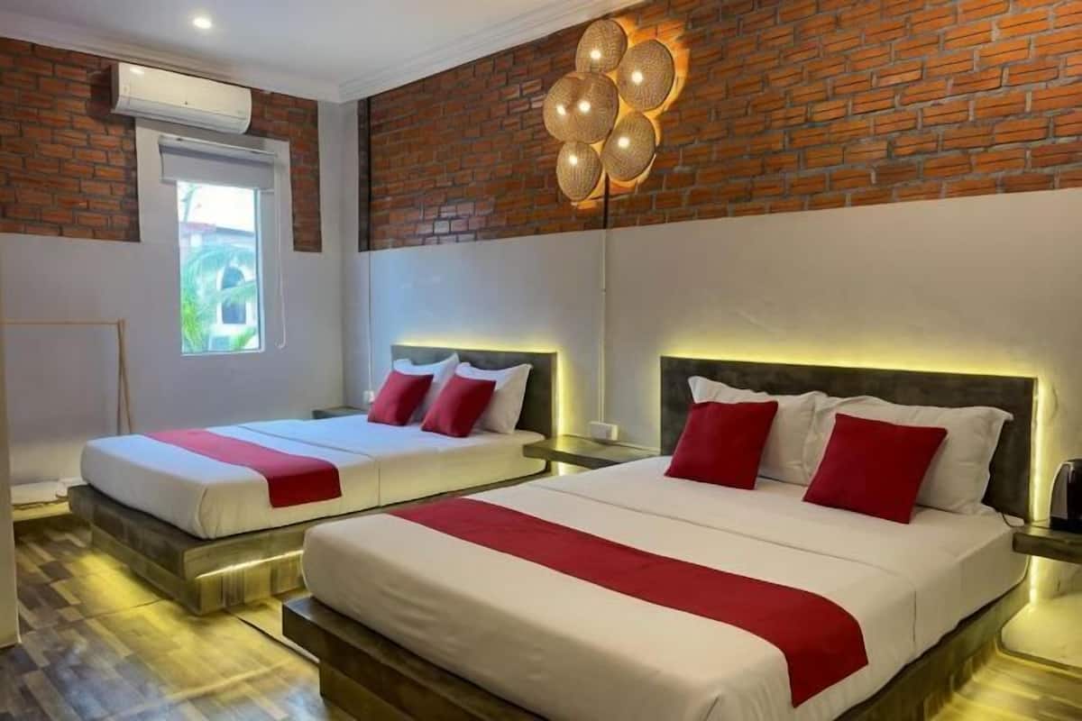 Une chambre d’hôtel avec deux lits, un mur en briques et un luminaire moderne.