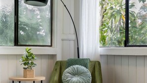 A room with a green armchair, a round wooden table, a floor lamp, and a bench. - Island Oasis Near Waterfalls and Hilo`s Markets (Hilo)
