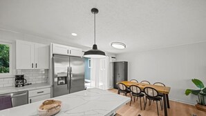 A modern kitchen with white cabinets, stainless steel appliances, and a marble island.