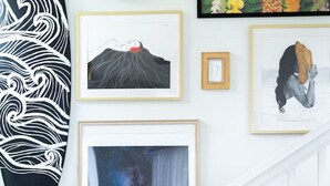 A staircase with white railings, a surfboard, and framed artworks including a volcano, a starry sky, and a floral pattern. - Garden Oasis, Walkable to Downtown Hilo (Hilo)