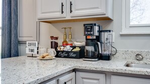 Una cocina con barra para café, que incluye una cafetera, tazas de café y un letrero que dice 'Coffee Time'.
