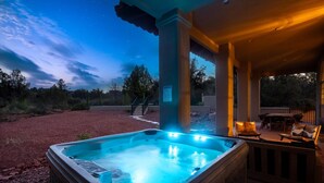 Un bain à remous situé sous une zone abritée, avec un ciel étoilé au-dessus.