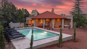 Une maison moderne dotée d’une piscine, d’un espace extérieur aménagé et d’un toit recouvert de tuiles rouges.