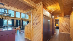 A wooden interior with a kitchen, dining area, and a staircase. - 6 Br Cabin~Hot Tub~Fire Pit~Min to Hatley Pointe (Mars Hill)