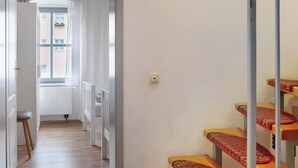 A hallway with a radiator, a window, and a staircase with patterned steps. - Holiday Apartment 'Alte Stadtmauer' with Shared Garden and Wi-Fi (Bamberg)