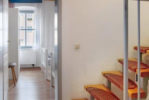 Un corridoio con termosifone, una finestra e una scala con gradini decorati.