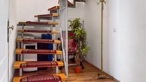 A staircase with patterned carpets, a potted plant, and a brass floor lamp. - Holiday Apartment 'Alte Stadtmauer' with Shared Garden and Wi-Fi (Bamberg)