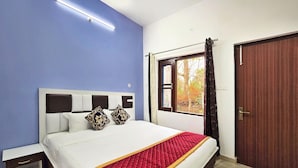 Une chambre à coucher avec un lit, une table de chevet, une fenêtre avec des rideaux et une porte.