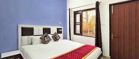 A bedroom with a bed, a bedside table, a window with curtains, and a door.