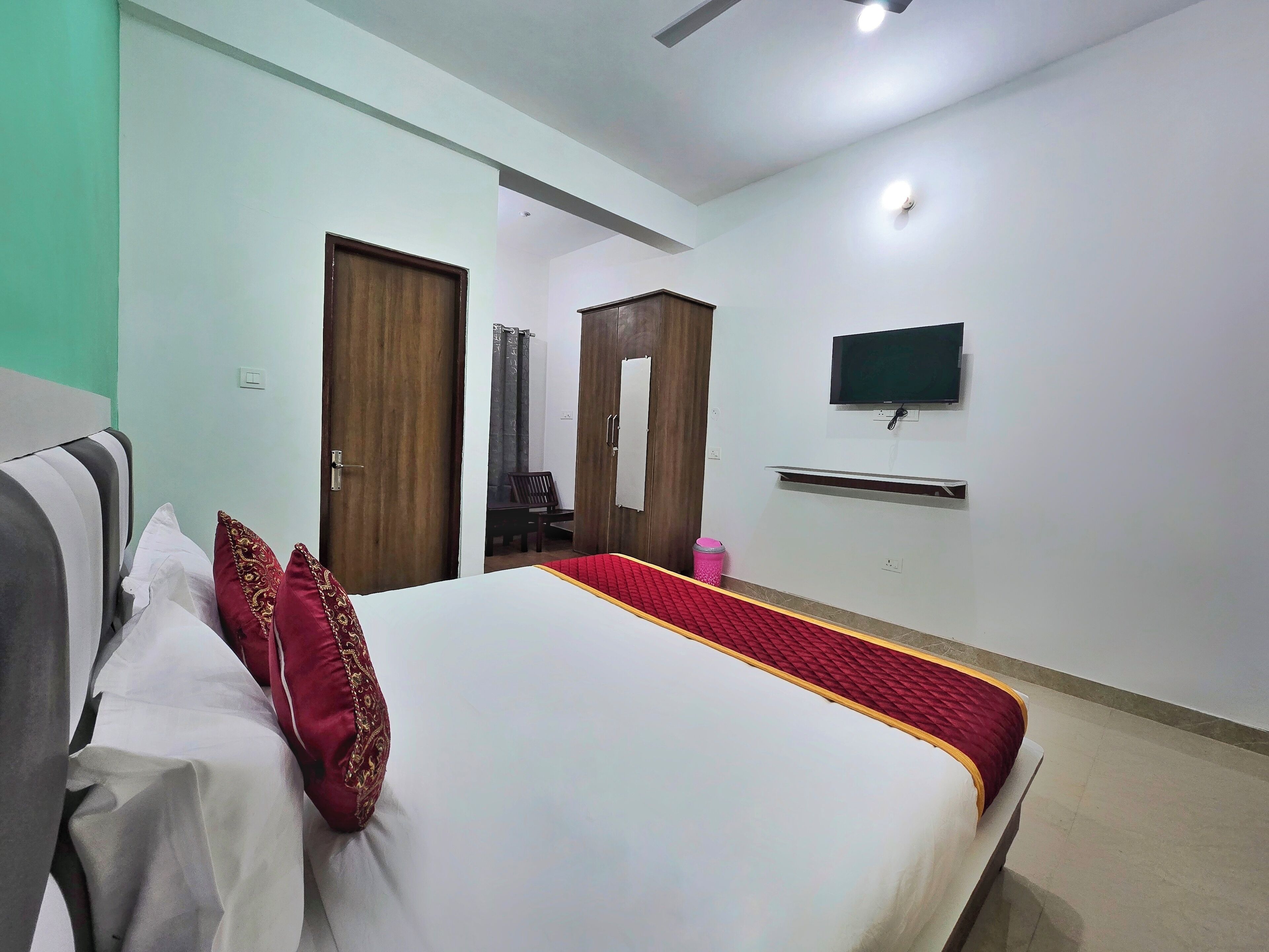 A hotel room with a bed, a television mounted on the wall, and a wardrobe.