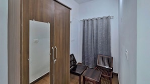 Une pièce comprenant une armoire, une chaise, une petite table et un rideau.
