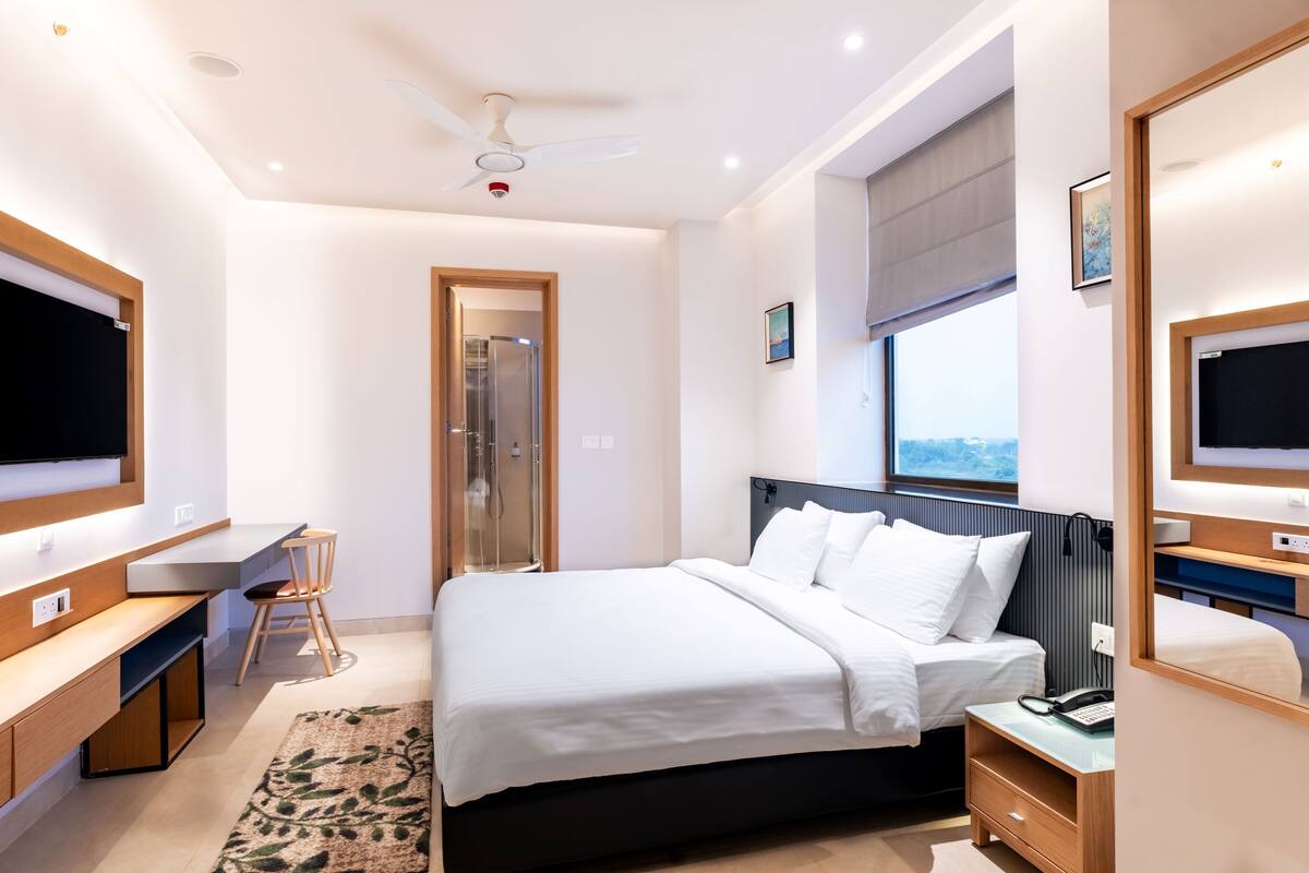 Ein modernes Schlafzimmer mit Bett, Nachttisch, Schreibtisch, Stuhl und einem großen Fenster.