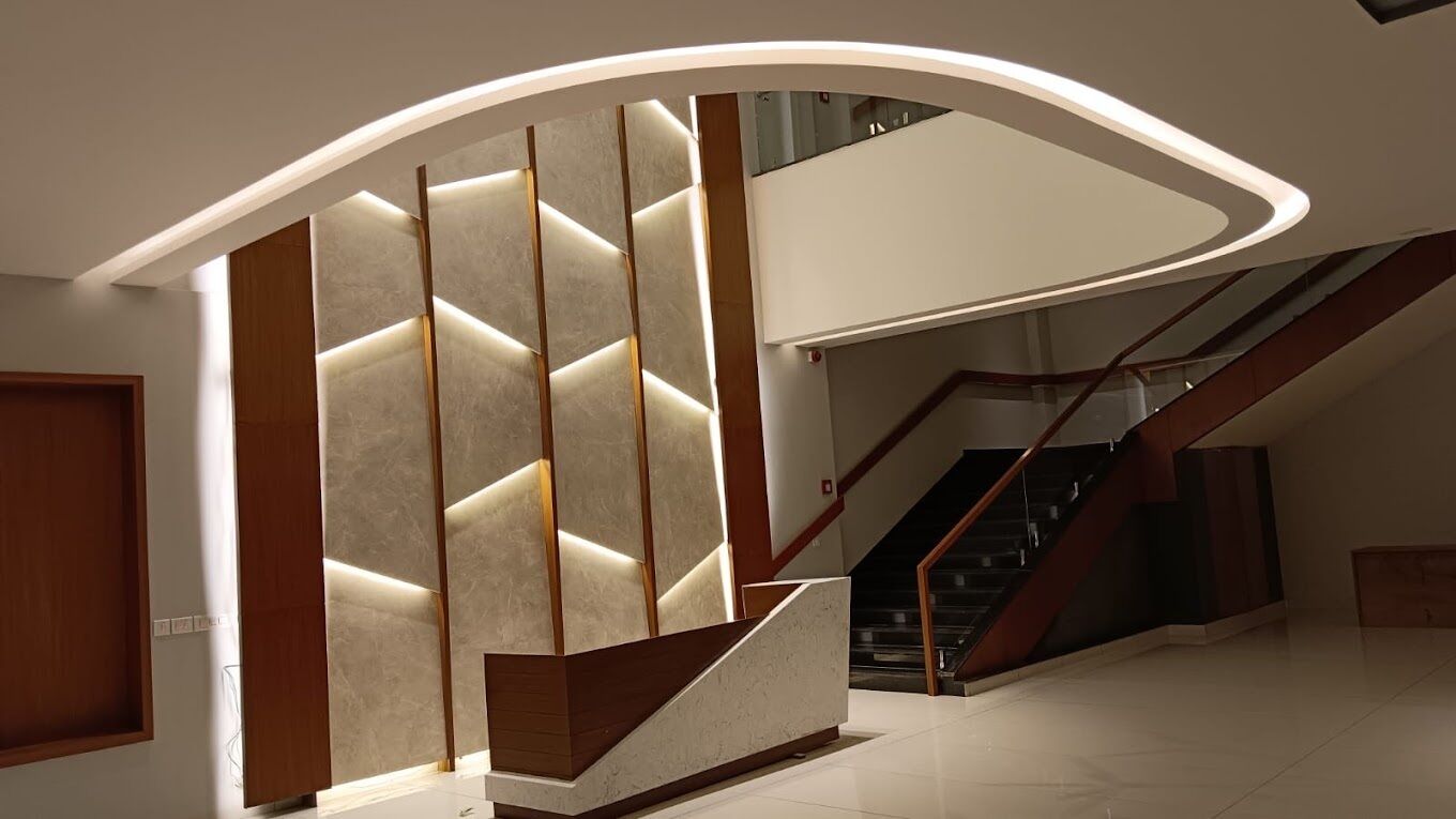 A modern interior with a curved staircase, a wooden reception desk, and a wall with illuminated panels.