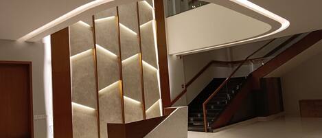 A modern interior with a curved staircase, a wooden reception desk, and a wall with illuminated panels.