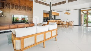 A modern living room with a large TV, wooden furniture, and a dining area. - Srimalen Villa by Kozystay - Canggu- (Canggu)