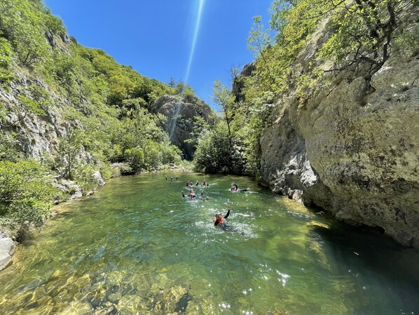 Un río cristalino rodeado de riscos rocosos y abundante vegetación.