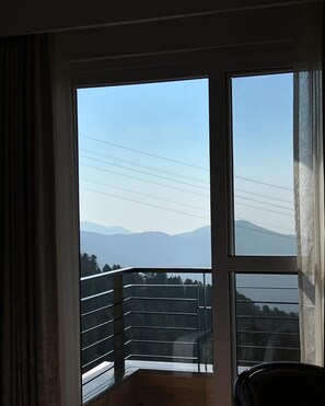 A room with a large window overlooking a mountainous landscape. - Jot Pass Hotel (Bhattiyat)