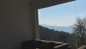 Una sala de estar moderna con un amplio ventanal que ofrece vistas a la montaña.