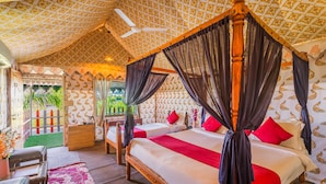 A four-poster bed with a canopy, two bedside tables, and a view of greenery outside. - The Rawla Tent Resort & Spa (Garudeshwar)