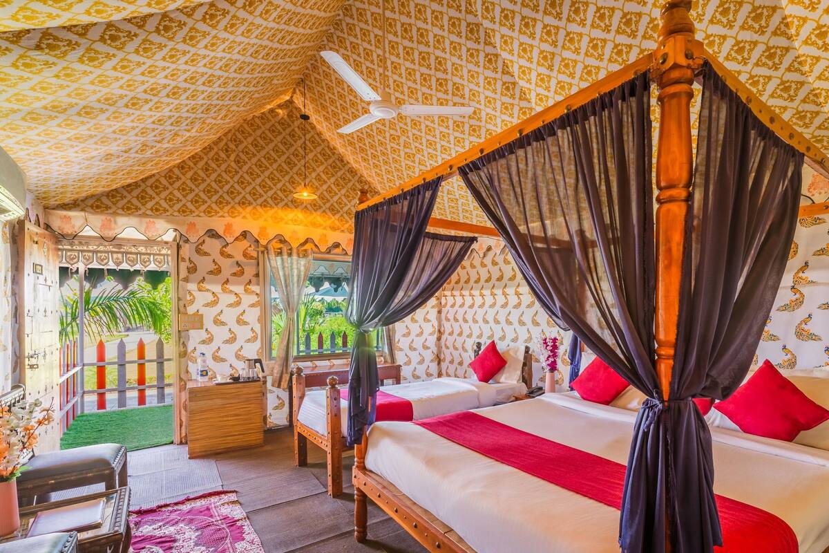 A four-poster bed with a canopy, two bedside tables, and a view of greenery outside.