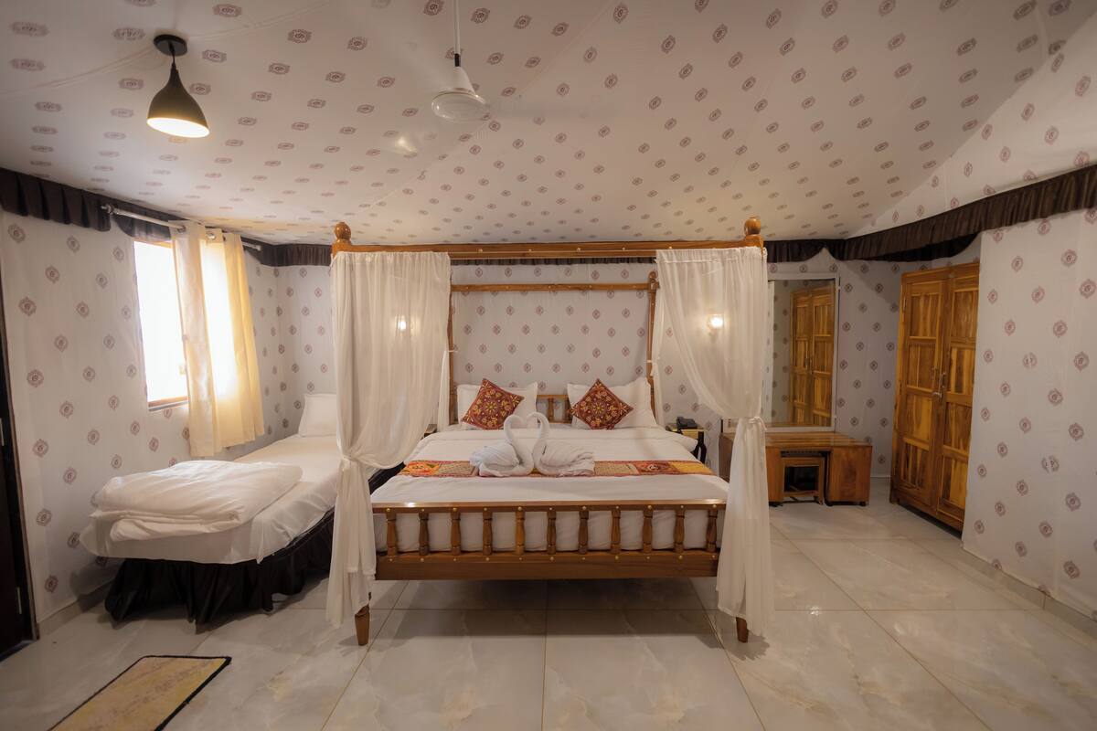A four-poster bed with white linens and decorative pillows, a wooden nightstand, and a mirror.