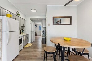 Uma cozinha moderna com armários brancos, uma tigela amarela sobre uma mesa de madeira e um espelho na parede.