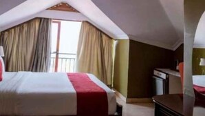 A hotel room with a bed, a desk, and a window with curtains. - Legend Hotel (Kigali)