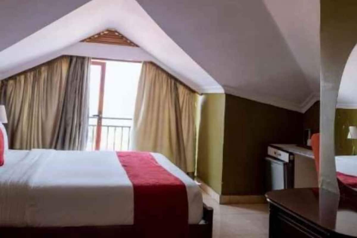 A hotel room with a bed, a desk, and a window with curtains.