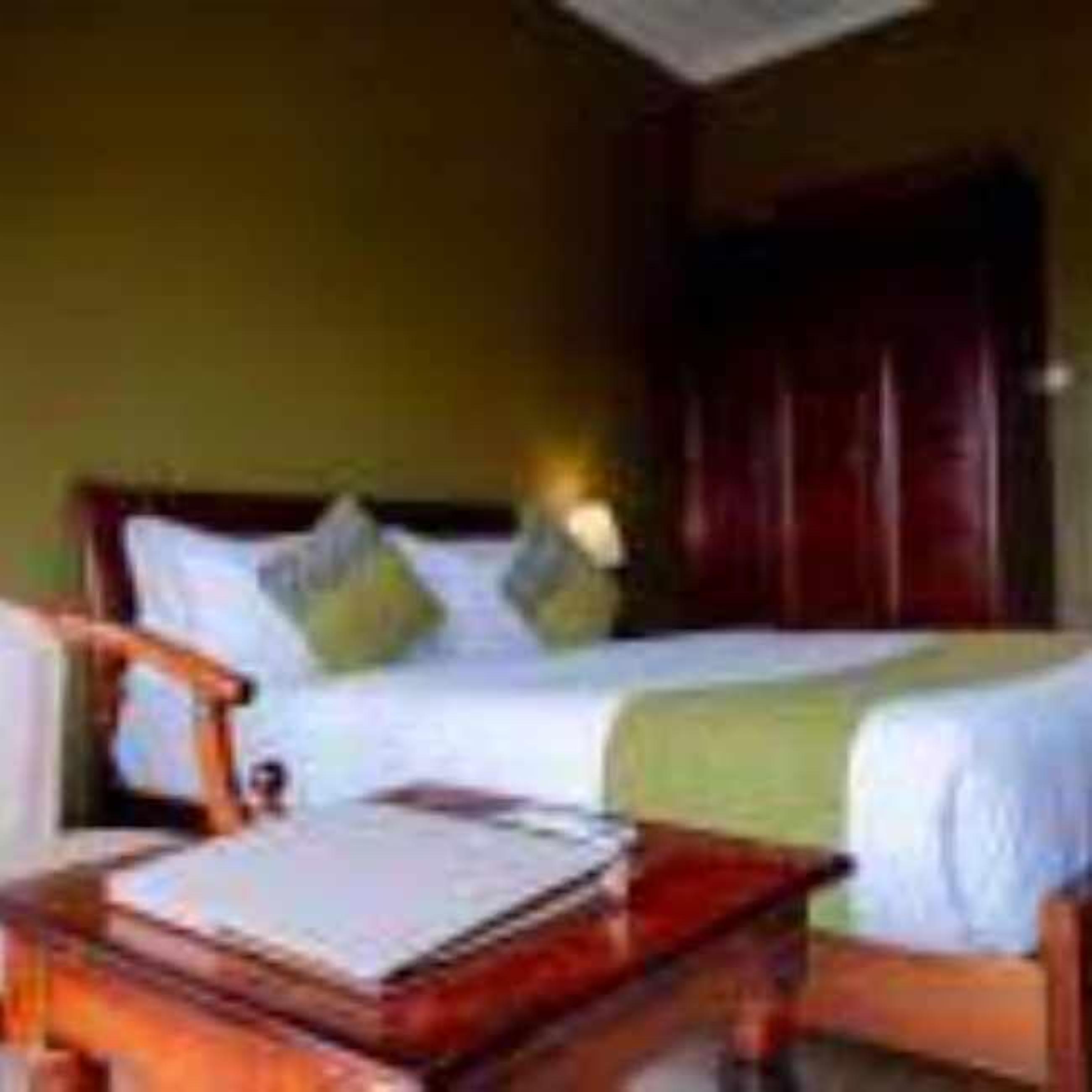 A hotel room with a bed, a wooden nightstand, and a chair.