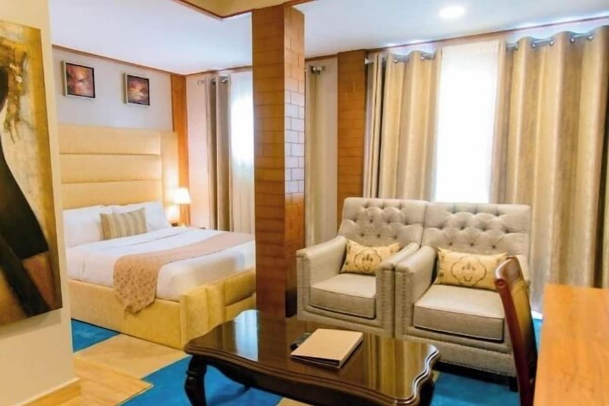 A hotel room with a bed, a sofa, a coffee table, and curtains.
