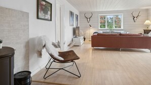 Ein modernes Wohnzimmer mit einem braunen Ledersessel, einem roten Sofa und einem weißen Kamin.