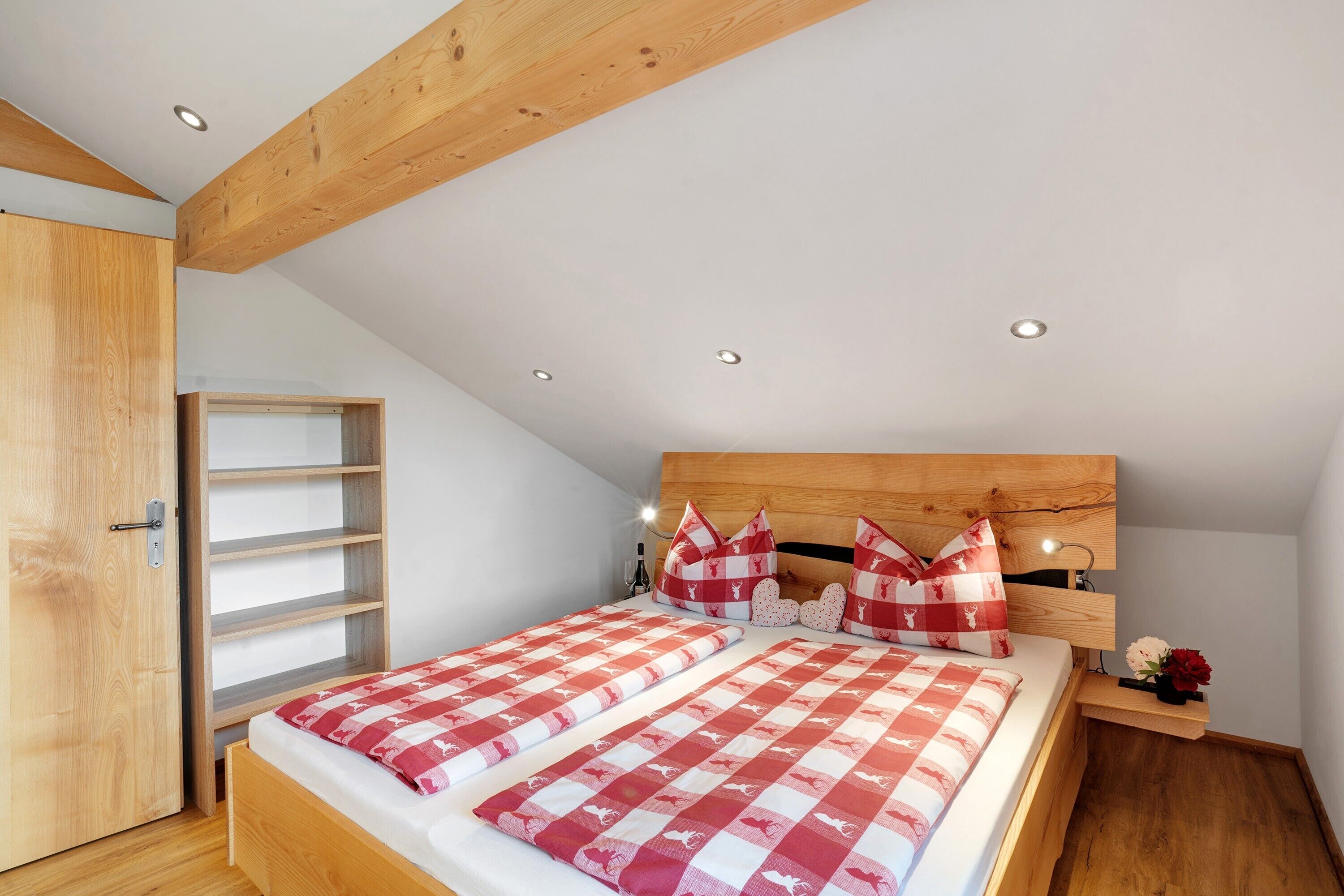 Une chambre à coucher avec une tête de lit en bois, un lit avec une literie à carreaux, une armoire en bois et des étagères intégrées.