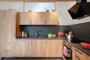 A modern kitchen with wooden cabinets, a black countertop, a built-in oven, and a microwave.