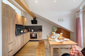 Una cocina moderna con armarios de madera, una mesa de comedor con platos y bebidas, y un banco.