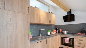 A modern kitchen with wooden cabinets, a stainless steel sink, and a built-in oven. - Apartment 'Neubau - Freundliche' with Mountain View, Shared Garden and Wi-Fi (Höslwang)