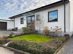 Ein modernes Haus mit gepflegtem Rasen, einer Treppe, die zum Eingang führt, und einer Garagentür.