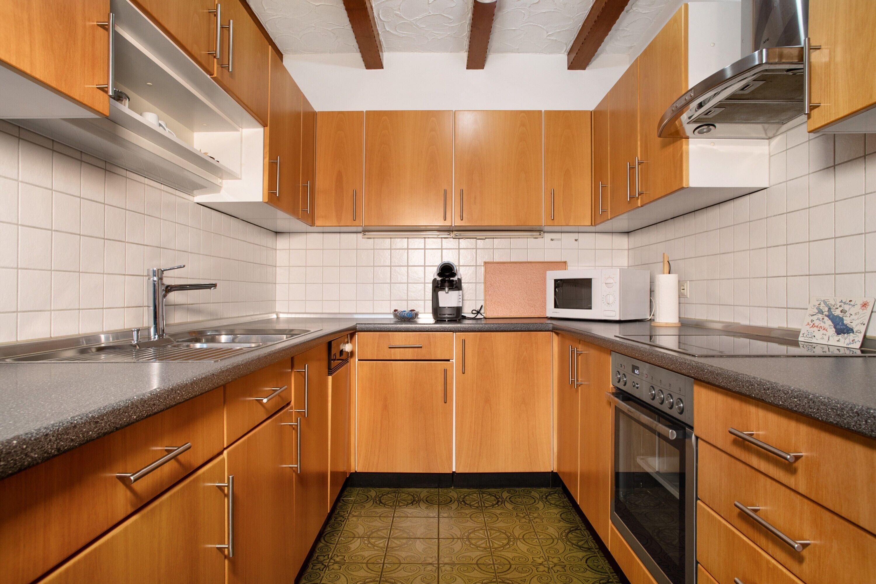 Eine Küche mit Holzausstattung, einer Mikrowelle, einem Backofen und einem Spülbecken.