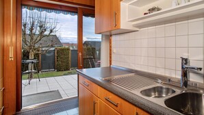 Een keuken met houten kastjes, een roestvrijstalen spoelbak en uitzicht op de achtertuin.