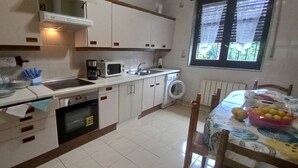 A compact kitchen with a microwave, oven, sink, and washing machine.