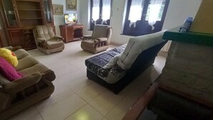 A living room with a sofa, armchairs, a coffee table, and a television.