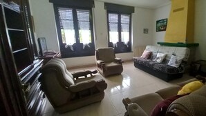 A living room with a sofa, armchairs, a coffee table, and a television.