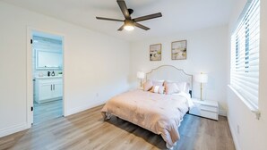 A bedroom with a bed, bedside lamps, a ceiling fan, and a view of a kitchen. - Tranquil 3-bedroom house in Austin with WiFi and AC (Austin)
