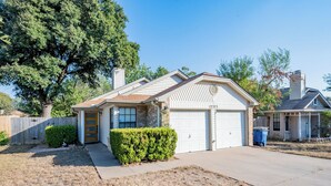 A single-story house with a garage, a front yard with a hedge, and a wooden fence. - Tranquil 3-bedroom house in Austin with WiFi and AC (Austin)