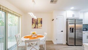 A modern kitchen with white cabinets, a stainless steel refrigerator, and a dining area with a round table and chairs. - Tranquil 3-bedroom house in Austin with WiFi and AC (Austin)